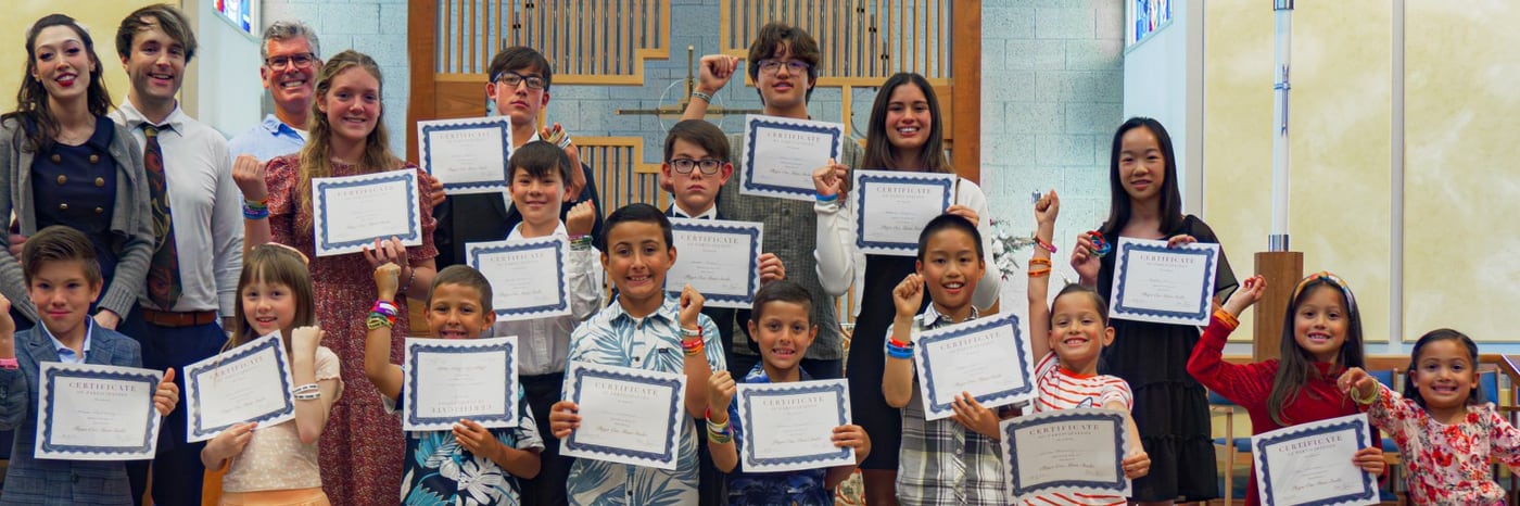 Students of every age lined up across the front of the hall, each holding a Player One certificate of participation.