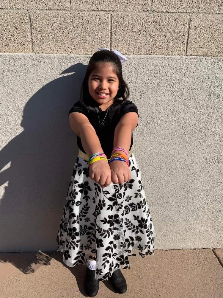 A Player One student outside after a recital, both wrists loaded with the coloured bands she has earned.